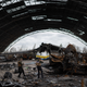 journalists photograph the remains of the Antonov An-225 airplane in a wrecked hanger at Hostomel airfield